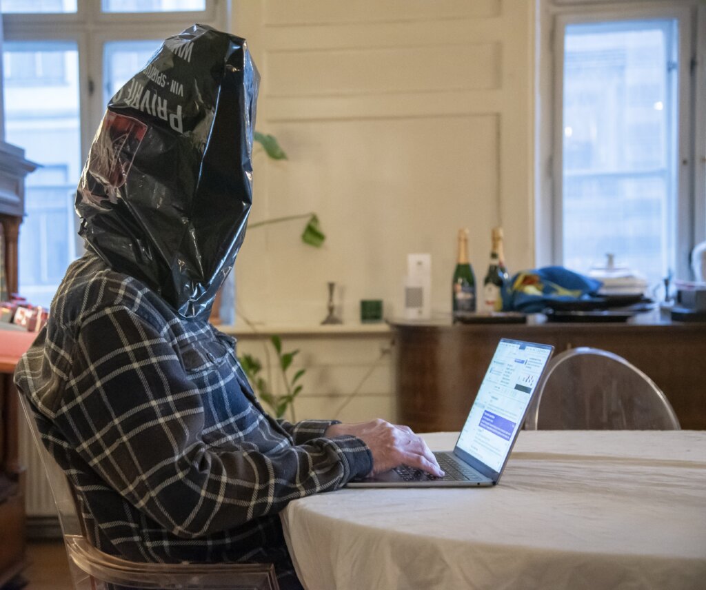 Knud Romer sidder med en pose over hovedet og skriver p&aring; computer for at illustrere, at han intet kan se