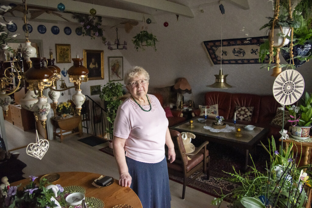 Brita st&aring;r smilende i sit hjem fyldt med planter og mange fine ting