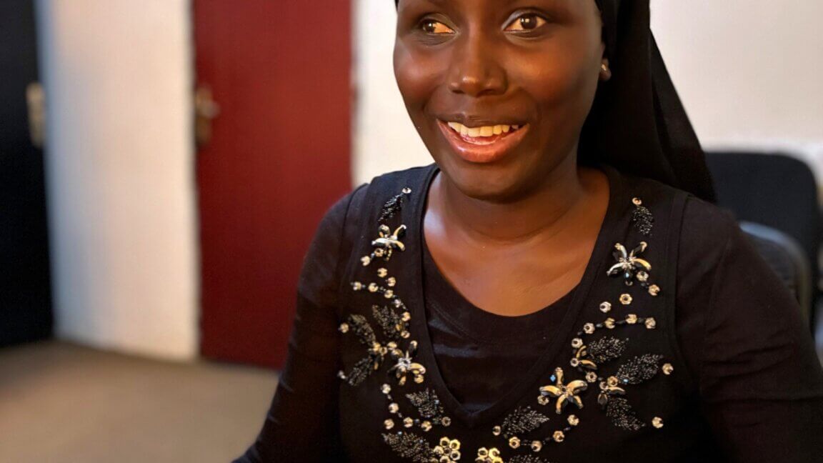 Mariatou sidder smilende med tørklæde på hovedet og paliet trøje