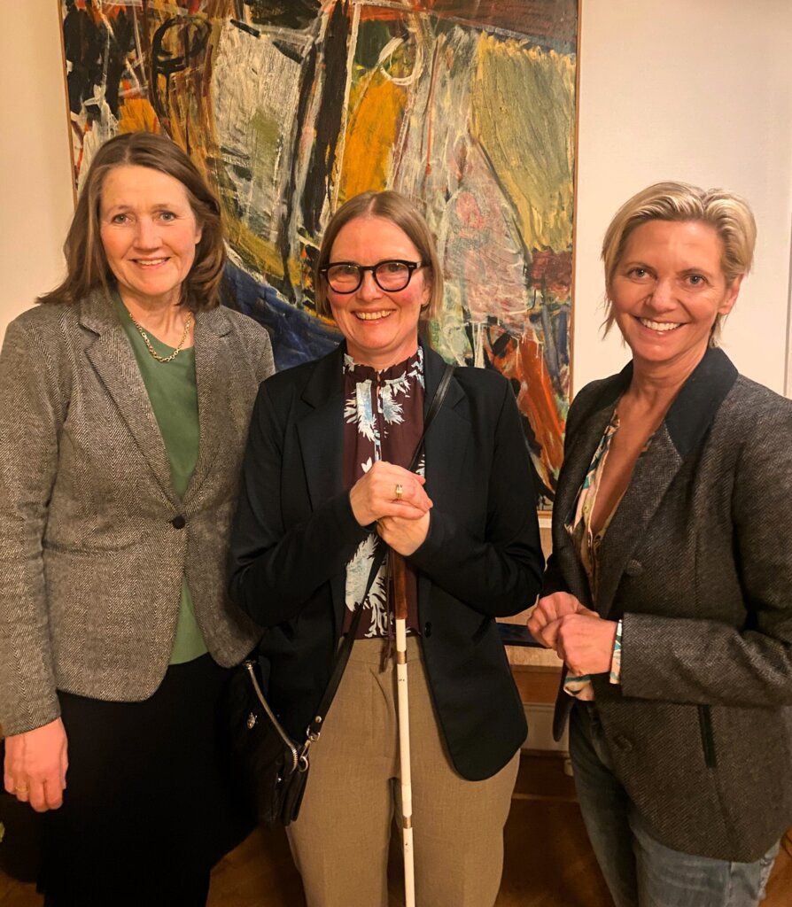 Diana st&aring;r i midten med sin blindestok. P&aring; hver side st&aring;r Helle Bonnesen og Chalotte Munch