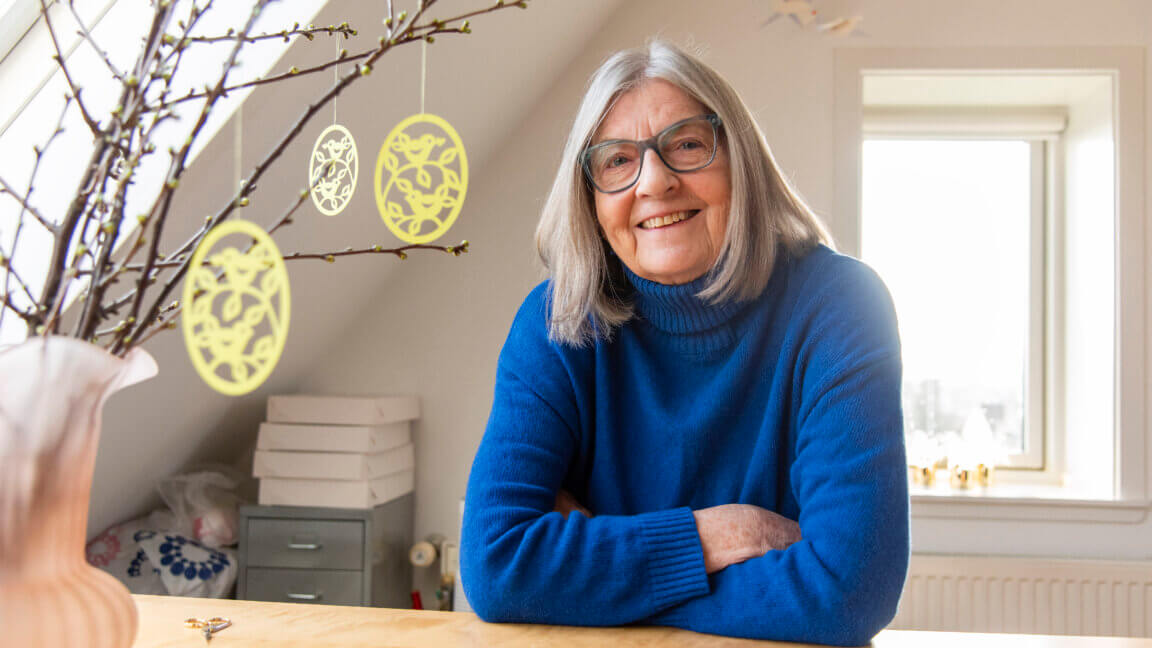 Portræt af Gitte. Ved siden af står en vase med forårsgrene, hvor påskepynten hænger