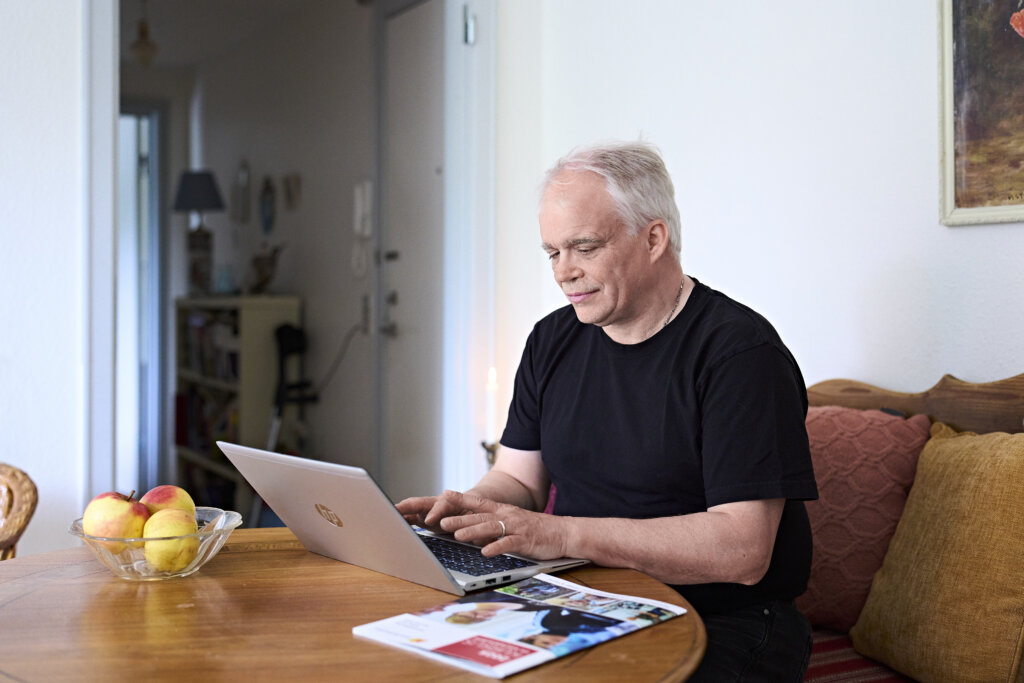 Poul arbejder p&aring; sin computer ved stuebordet