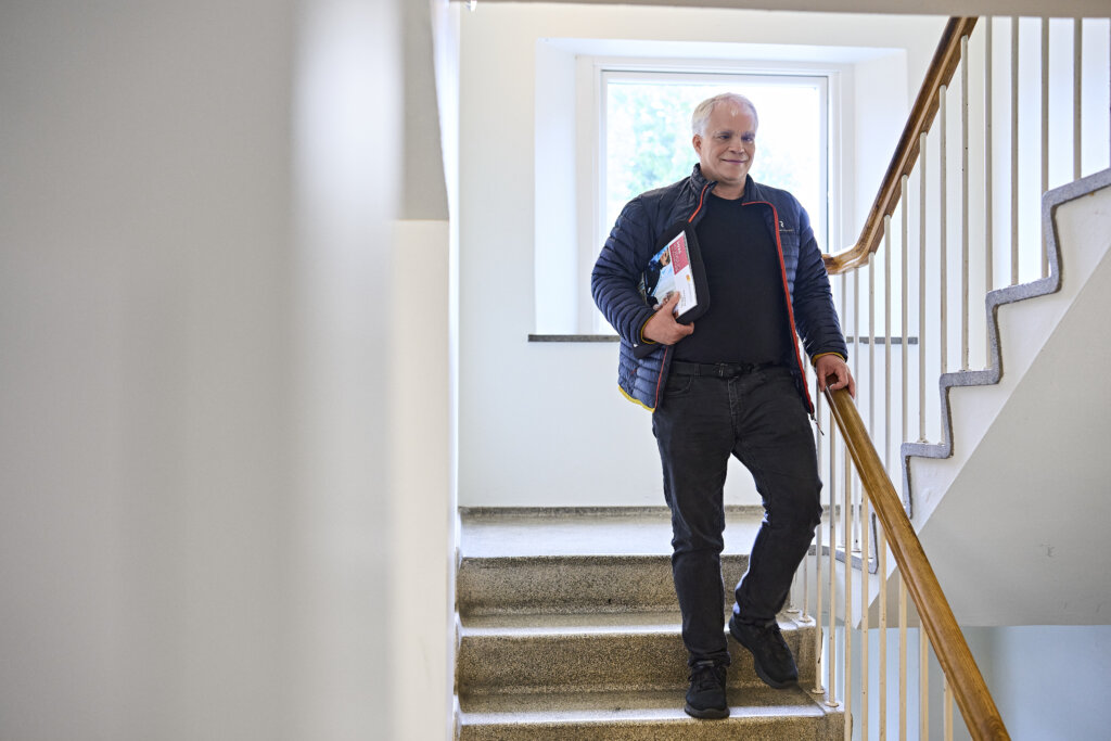 Poul g&aring;r ned ad en trappe. Under armen b&aelig;rer han kursuskataloget fra Dansk Blindesamfund