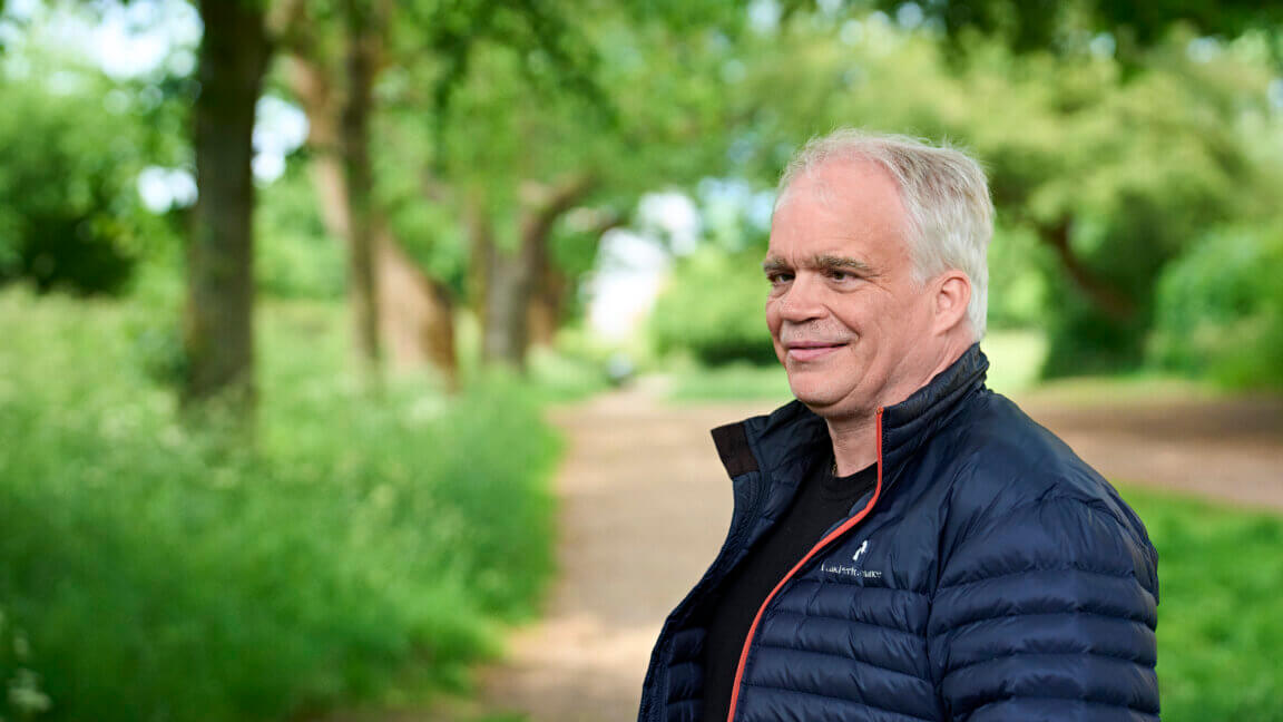 Portræt af smilende Poul, der står i en park