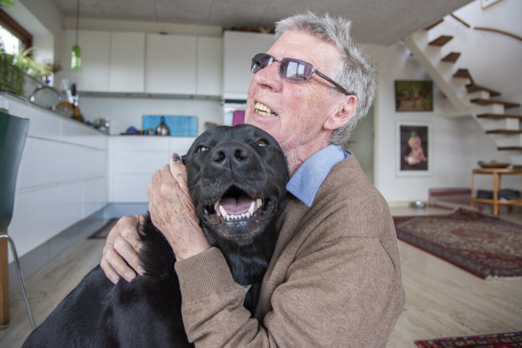 Hans Verner sidder på gulvet og krammer Siffi, en sort labrador