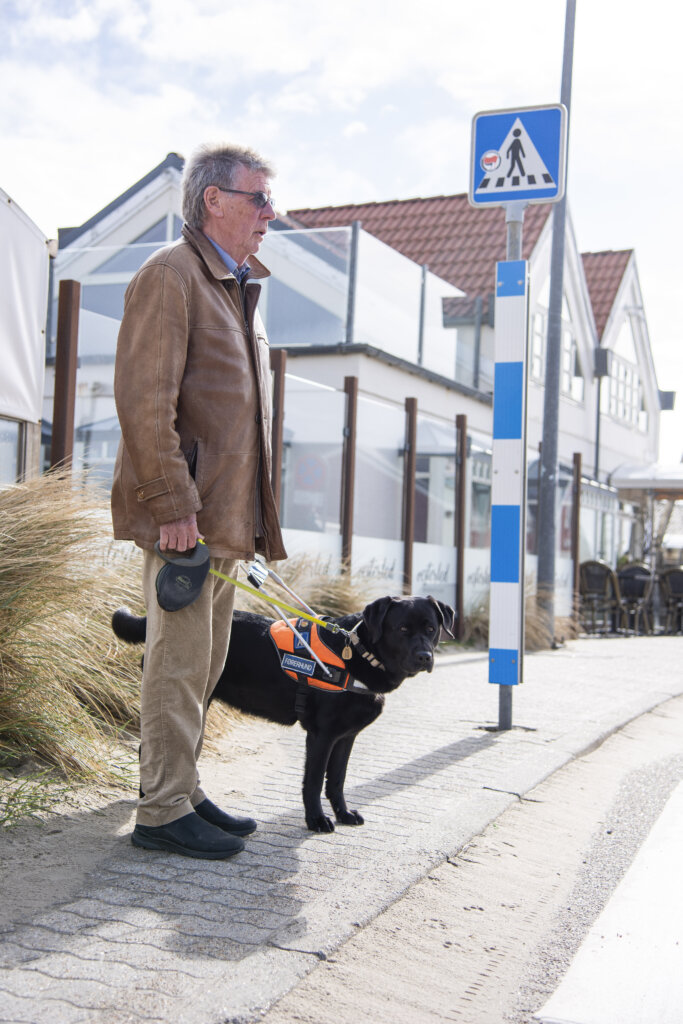 Hans Verner og førerhunden Siffi, en sort labrador, står ved en kant og er klar til at krydse en fodgængerovergang