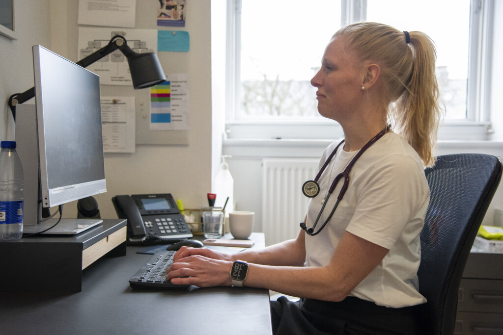 Stine sidder ved en computer i et konsultationsrum