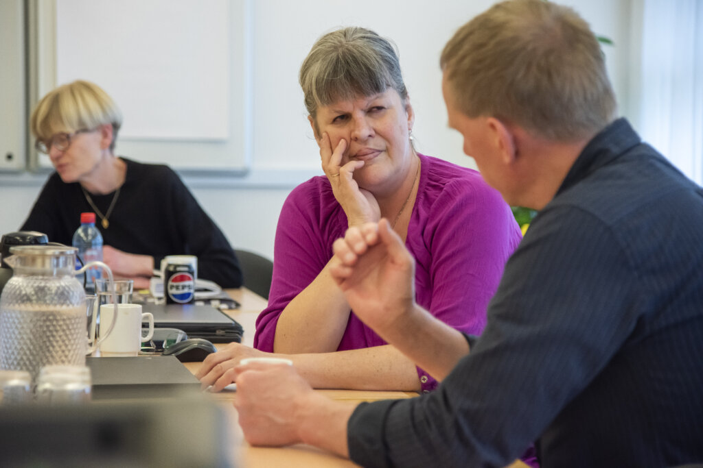 To deltagere diskuterer et emne. I baggrunden ses underviseren Helle