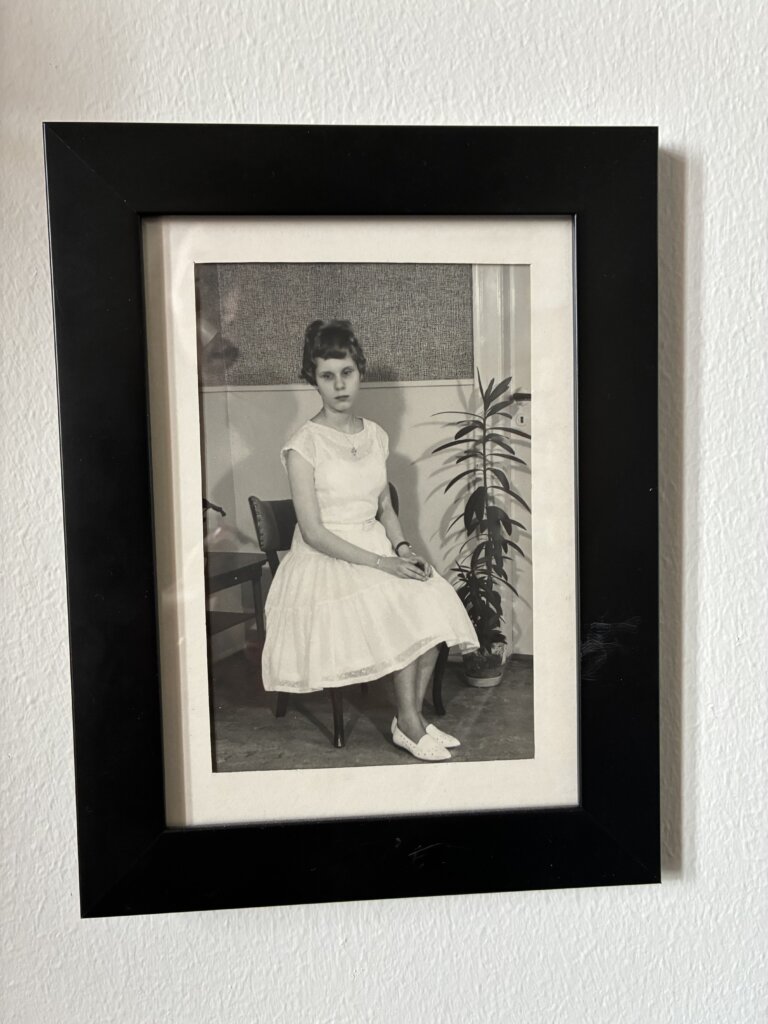 Billede i sort/hvid af Rita som ung, hvor hun sidder med en fin dansekjole