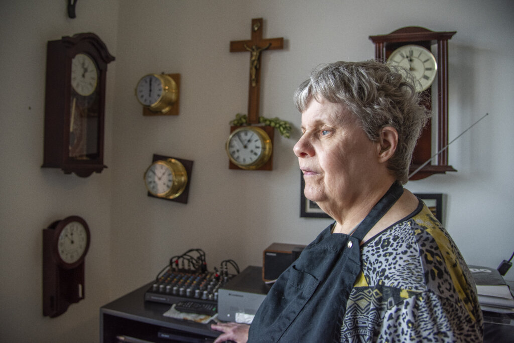 Rita fra siden, der st&aring;r i sin stue med mange ure p&aring; v&aelig;ggen