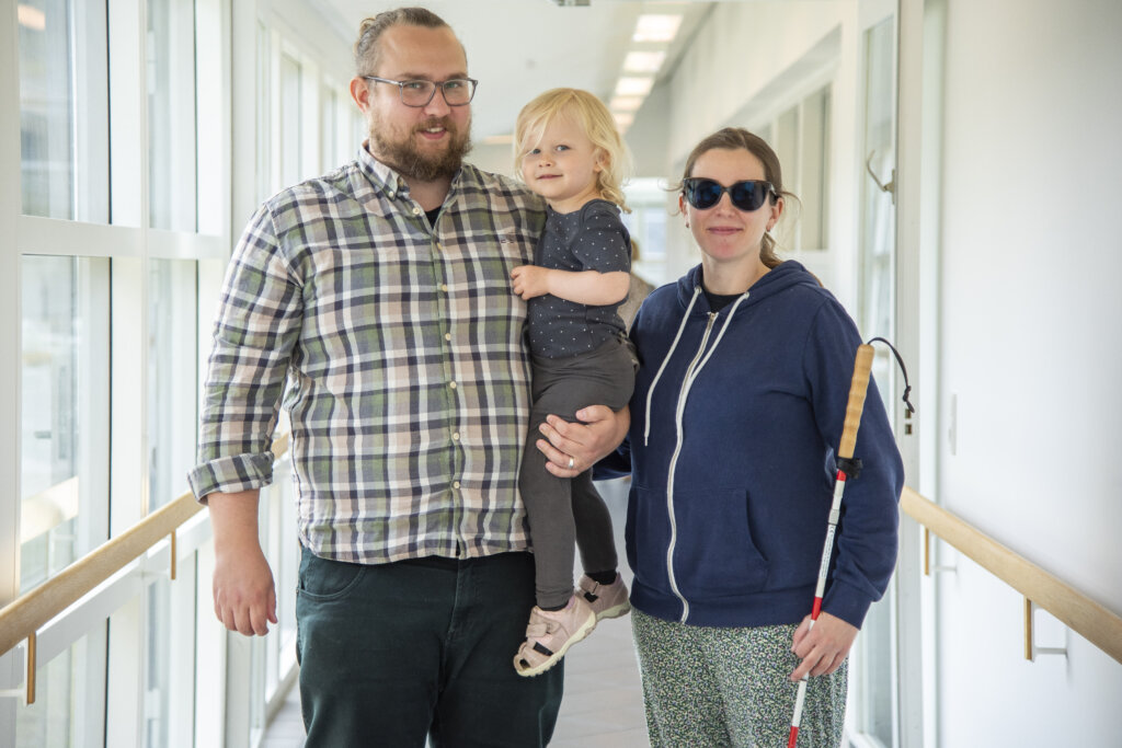 Patrick holder Saga p&aring; armen. Ved siden af st&aring;r Emilie med sin blindestok