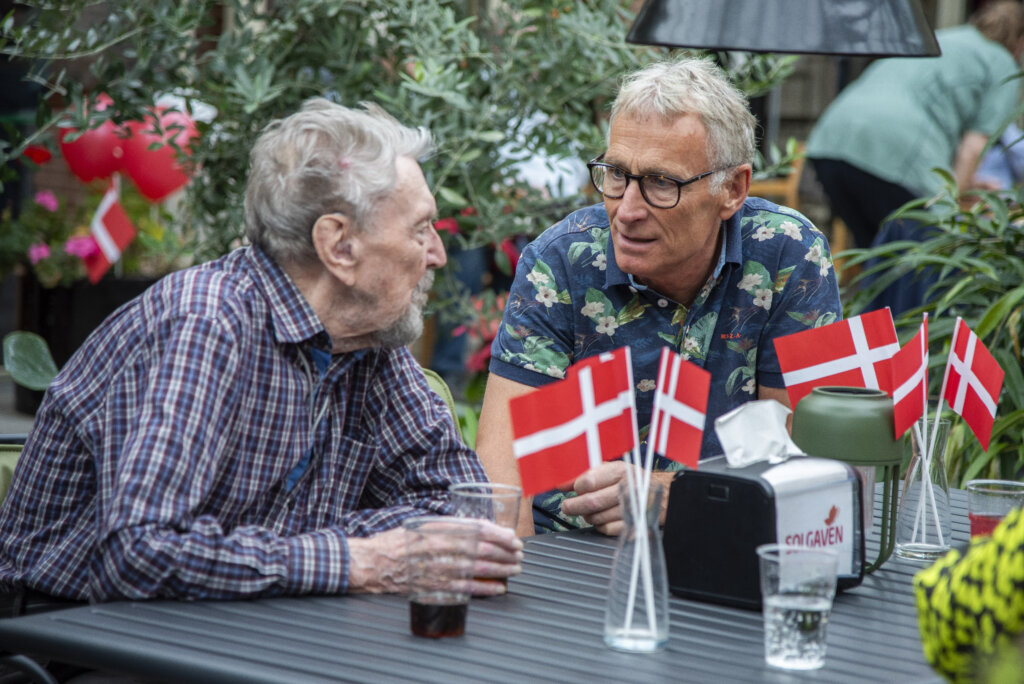 Gæster snakker i Vinterhaven med flag på bordet