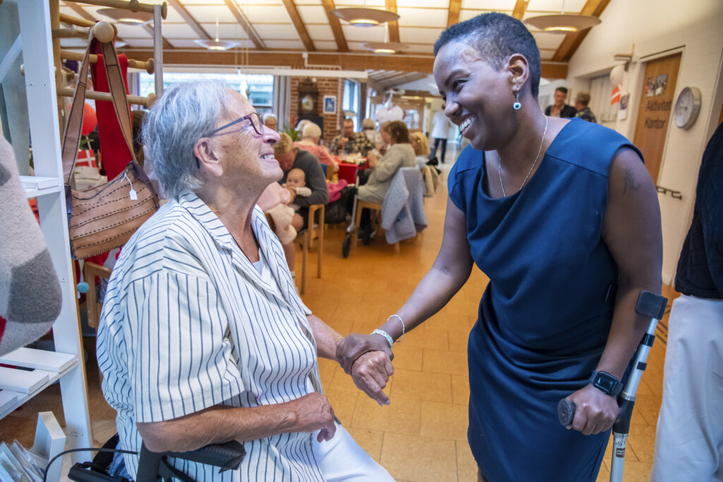 Konsulent Mona hilser på en beboer, som sidder på en rollator