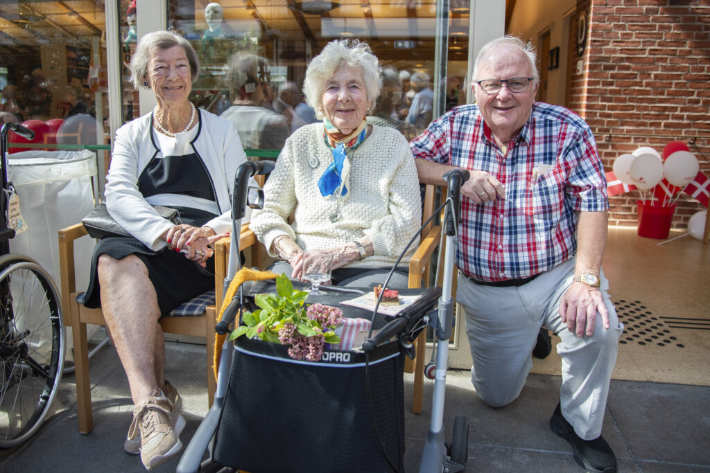 Bjarke sidder ved siden af sin mor Dagmar, der har en rollator holdende foran med blomster og kage på