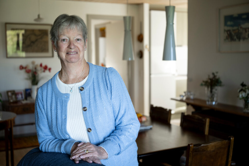Christina læner sig op af en lænestol i stuen