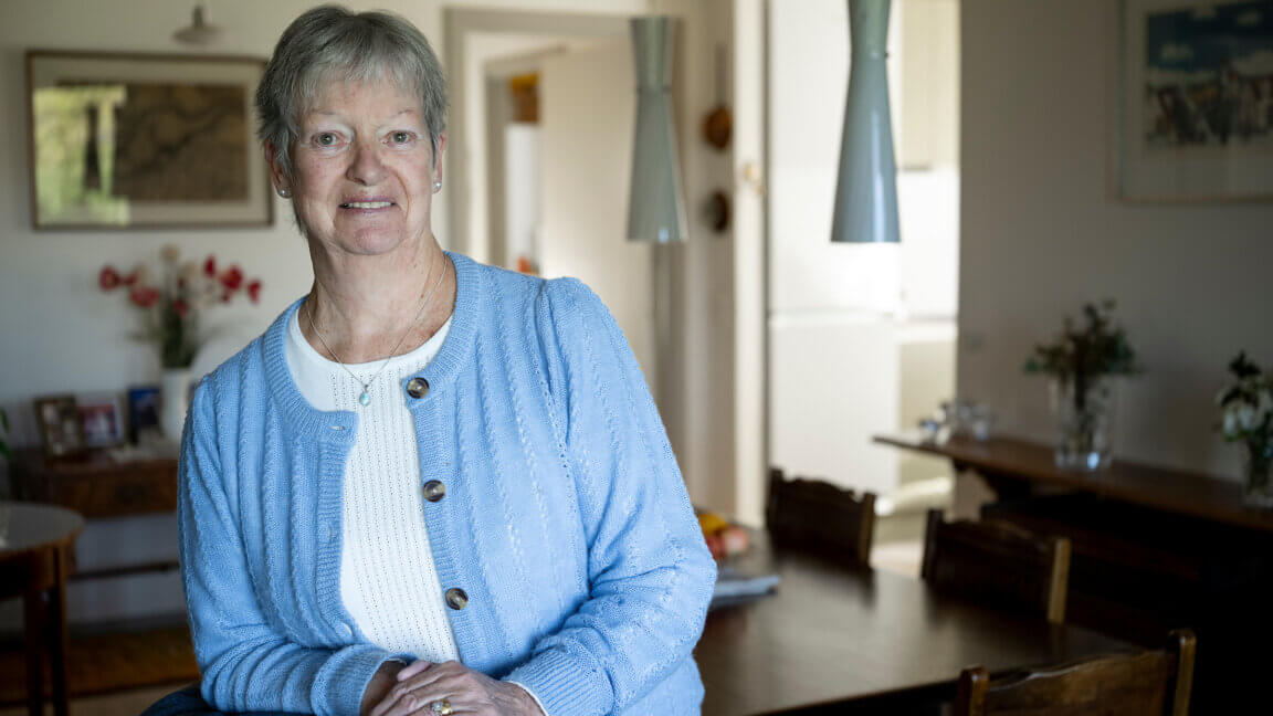 Christina læner sig op af en lænestol i stuen