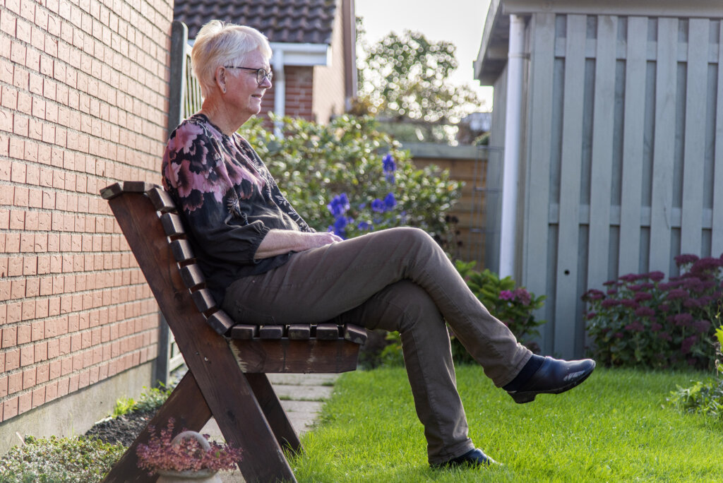 Hanne sider p&aring; sin b&aelig;nk i haven