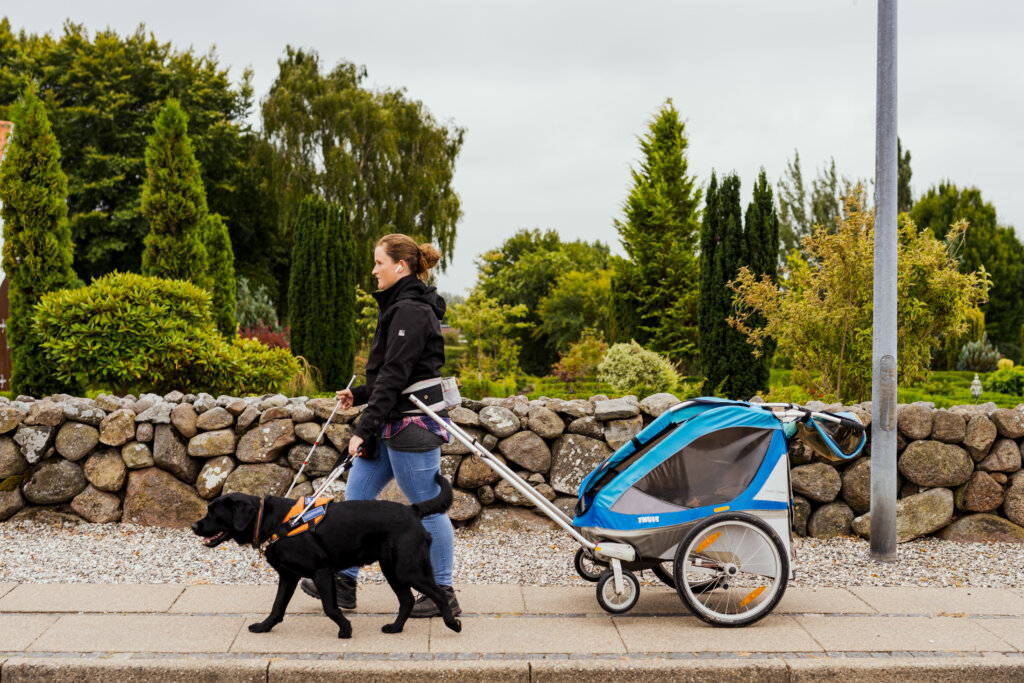 Ann-Sofie og sin førerhund går afsted med cykelanhængeren som anvender i dagligdagen fx når der skal afleveres børn.